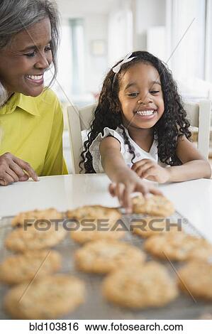 Stock Photograph - African American grandmother and granddaughter baking cookies. Fotosearch