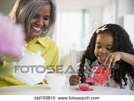 Stock Photography - African American grandmother and granddaughter having tea party. Fotosearch