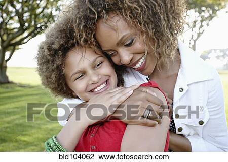 Stock Image - African American mother and daughter hugging. Fotosearch