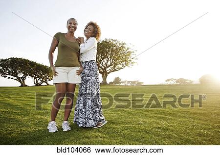 Stock Photograph - African American mother and daughter standing in park. Fotosearch