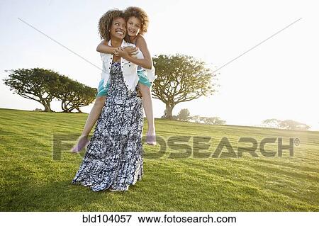 Stock Photo - African American mother giving daughter a piggyback ride. Fotosearch