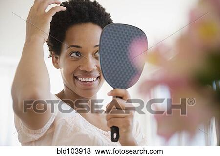 African American woman checking hair in mirror View Large Photo Image Stock Photo - African American woman checking hair in mirror. Fotosearch