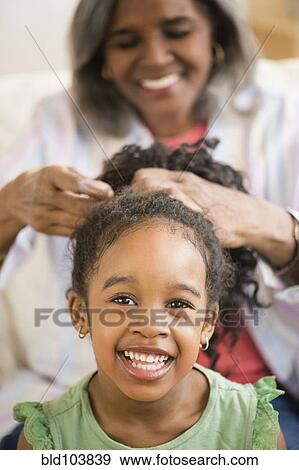 Stock Photo - African American woman fixing granddaughter's hair. Fotosearch