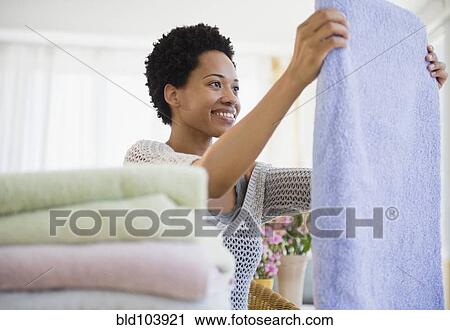 Stock Image - African American woman folding towels. Fotosearch