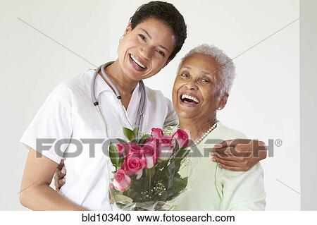Stock Image - African American woman hugging nurse. Fotosearch
