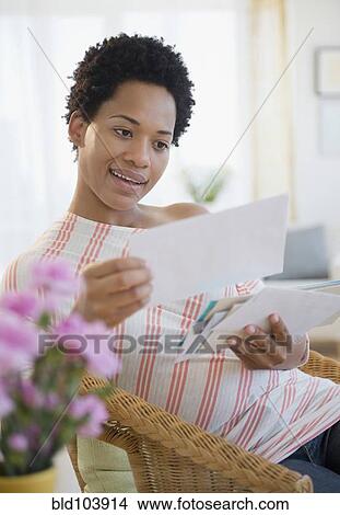 Picture - African American woman looking at mail. Fotosearch