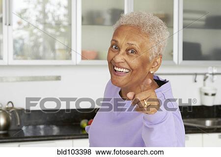Stock Photo - African American woman pointing in kitchen. Fotosearch