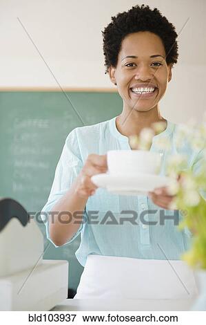 Stock Photo - African American woman serving coffee. Fotosearch