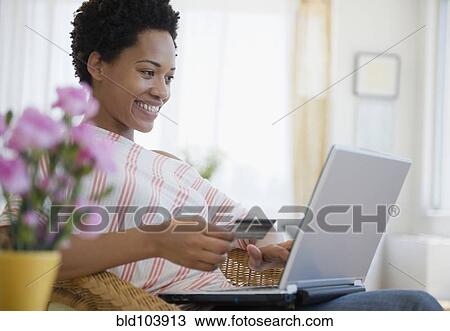 Stock Image - African American woman shopping online with credit card. Fotosearch
