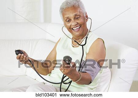 Stock Image - African American woman taking her blood pressure. Fotosearch