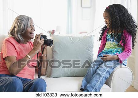Stock Image - African American woman taking pictures of granddaughter. Fotosearch