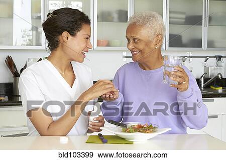 Stock Photo - African American woman taking medication and eating lunch. Fotosearch