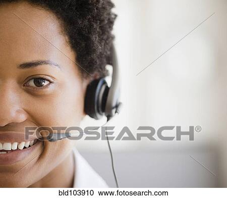 Stock Image - African American woman talking into headset. Fotosearch