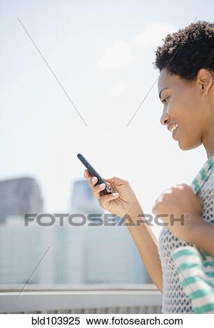 Stock Photography - African American woman using cell phone. Fotosearch