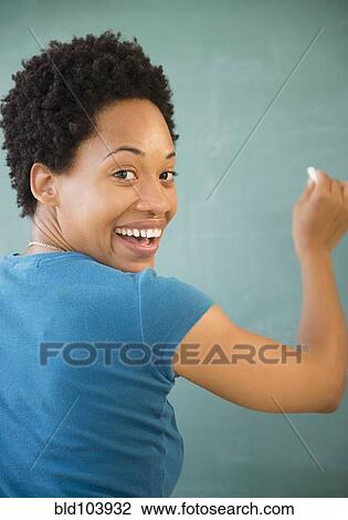 Stock Image - African American woman writing on blackboard. Fotosearch