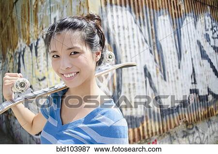 Asian woman carrying skateboard View Large Photo Image Stock Photo - Asian woman carrying skateboard. Fotosearch
