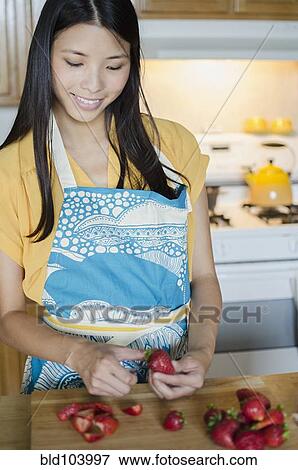 Stock Photo - Asian woman cutting strawberries. Fotosearch