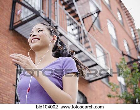 Stock Image - Asian woman jogging and listening to music. Fotosearch