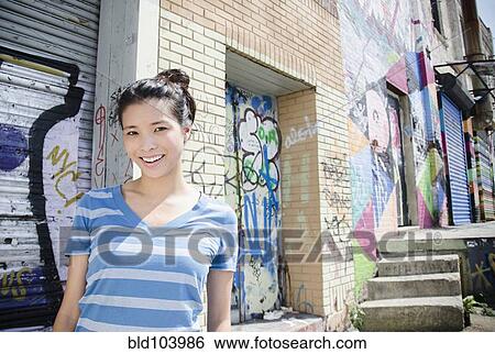 Stock Photograph - Asian woman near urban graffiti. Fotosearch