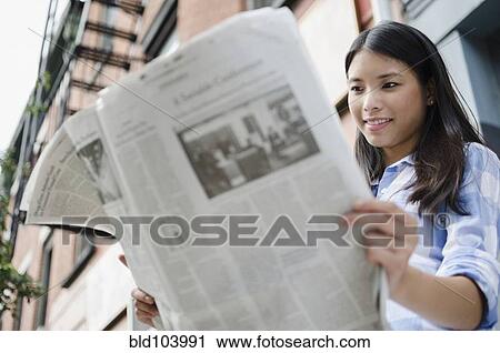 Stock Image - Asian woman reading newspaper. Fotosearch