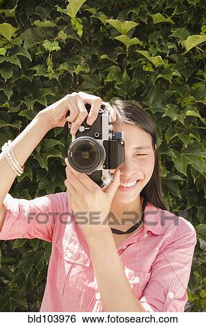 Stock Photograph - Asian woman taking photographs. Fotosearch