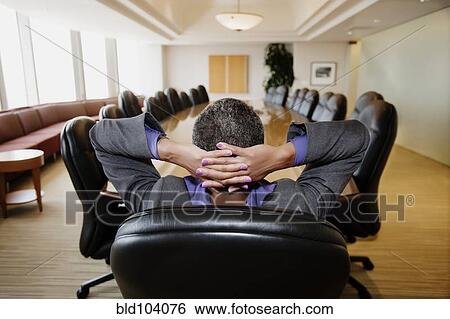 Stock Photograph - Black businesswoman sitting in empty conference room. Fotosearch