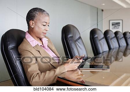 Black businesswoman using cell phone in conference room View Large Photo Image Picture - Black businesswoman using cell phone in conference room. Fotosearch
