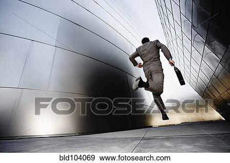 Stock Photo - Businessman running down urban alley. Fotosearch