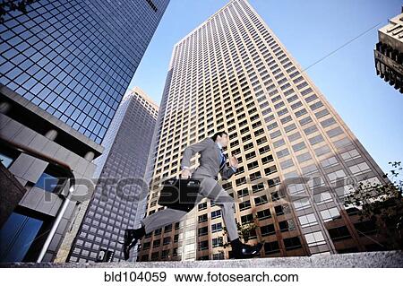 Stock Photo - Businessman running past highrise building. Fotosearch