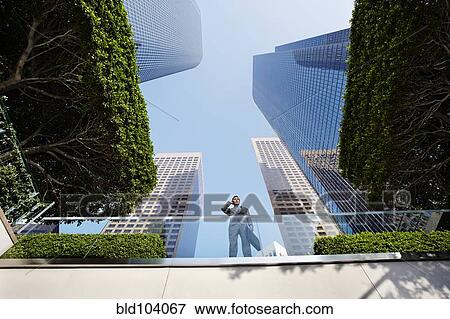 Stock Photo - Businessman standing on balcony talking on cell phone. Fotosearch