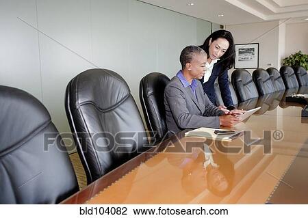 Stock Image - Businesswomen working together in conference room. Fotosearch