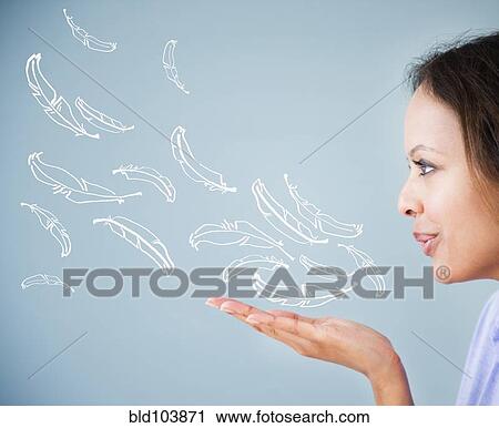 Stock Image - Cape Verdean woman blowing illustrations of feathers. Fotosearch