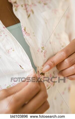 Stock Photograph - Cape Verdean woman buttoning shirt. Fotosearch