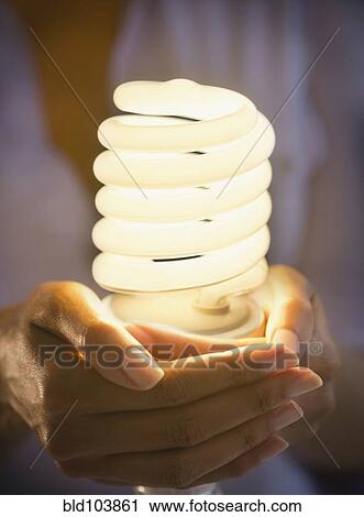 Stock Image - Cape Verdean woman holding CFL light bulb. Fotosearch