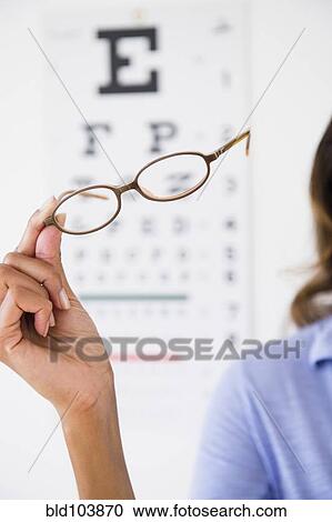 Stock Image - Cape Verdean woman holding eyeglasses. Fotosearch
