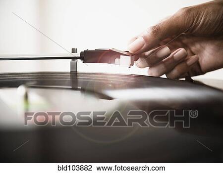 Stock Image - Cape Verdean woman listening to vinyl record. Fotosearch