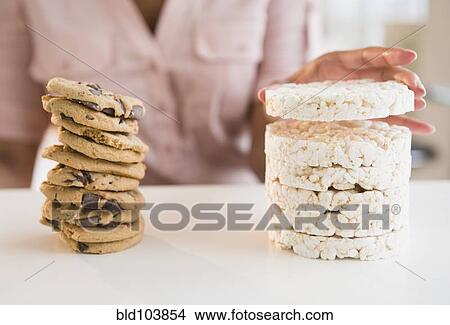 Picture - Cape Verdean woman stacking cookies and rice cakes. Fotosearch