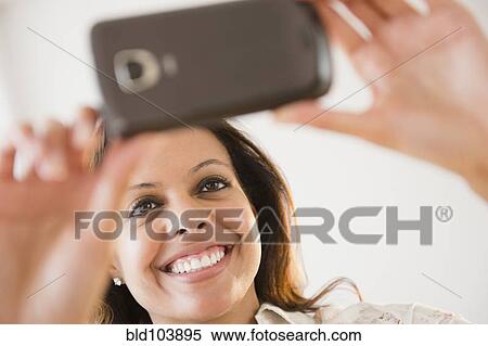 Stock Photography - Cape Verdean woman taking photograph with cell phone. Fotosearch