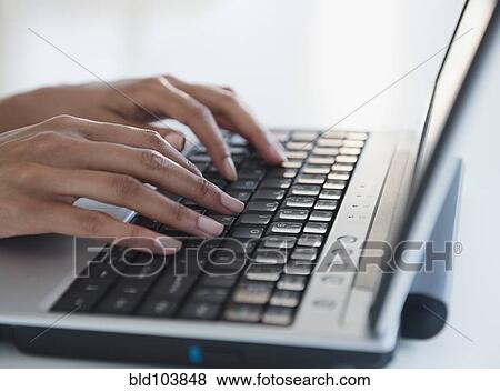 Stock Photo - Cape Verdean woman typing on laptop. Fotosearch