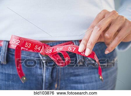 Stock Photograph - Cape Verdean woman using tape measure as belt. Fotosearch