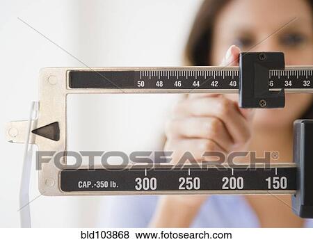 Stock Photo - Cape Verdean woman weighing herself. Fotosearch