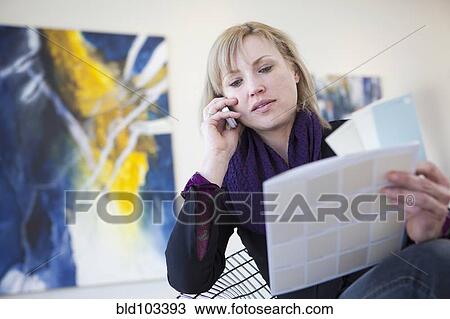 Stock Image - Caucasian art gallery owner talking on cell phone. Fotosearch