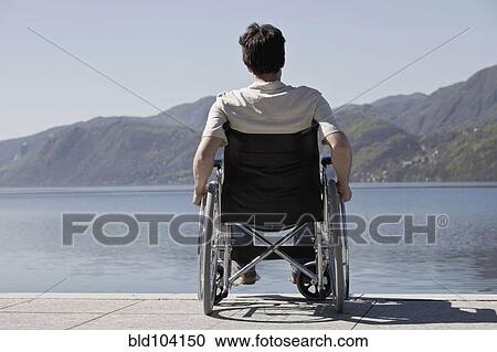 Stock Image - Caucasian man in wheelchair sitting on dock. Fotosearch