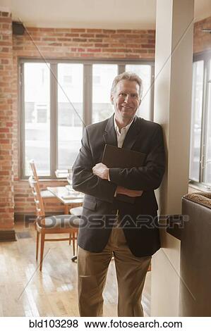 Stock Photo - Caucasian owner standing in restaurant. Fotosearch