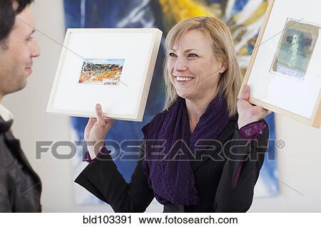 Caucasian woman showing paintings to customer View Large Photo Image Stock Image - Caucasian woman showing paintings to customer. Fotosearch
