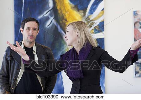 Stock Image - Caucasian woman talking to customer in art gallery. Fotosearch