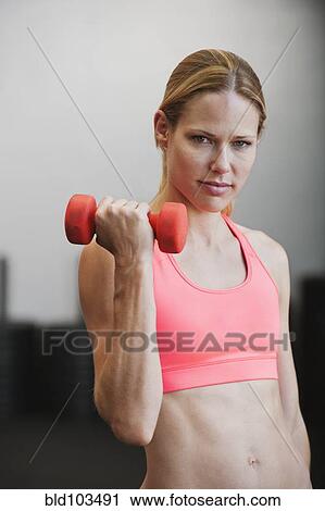 Stock Image - Caucasian woman using dumbbell. Fotosearch