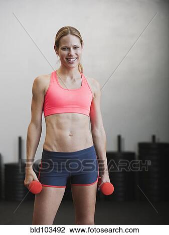 Stock Image - Caucasian woman using dumbbells. Fotosearch