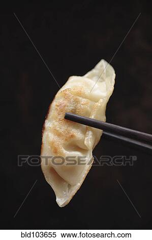 Chopsticks holding Asian dumpling View Large Photo Image Stock Photography - Chopsticks holding Asian dumpling. Fotosearch