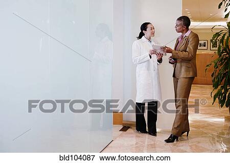 Stock Photo - Doctor and businesswoman using digital tablet. Fotosearch
